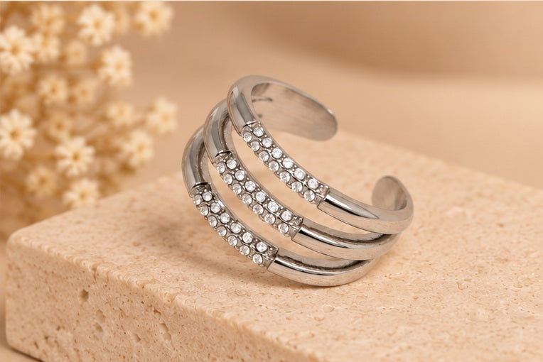 BAGUE CAMILLIA ARGENTÉE posée sur fond beige