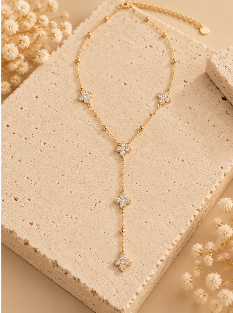 Collier Inaya doré avec motifs scintillants et retombée posé sur fond beige