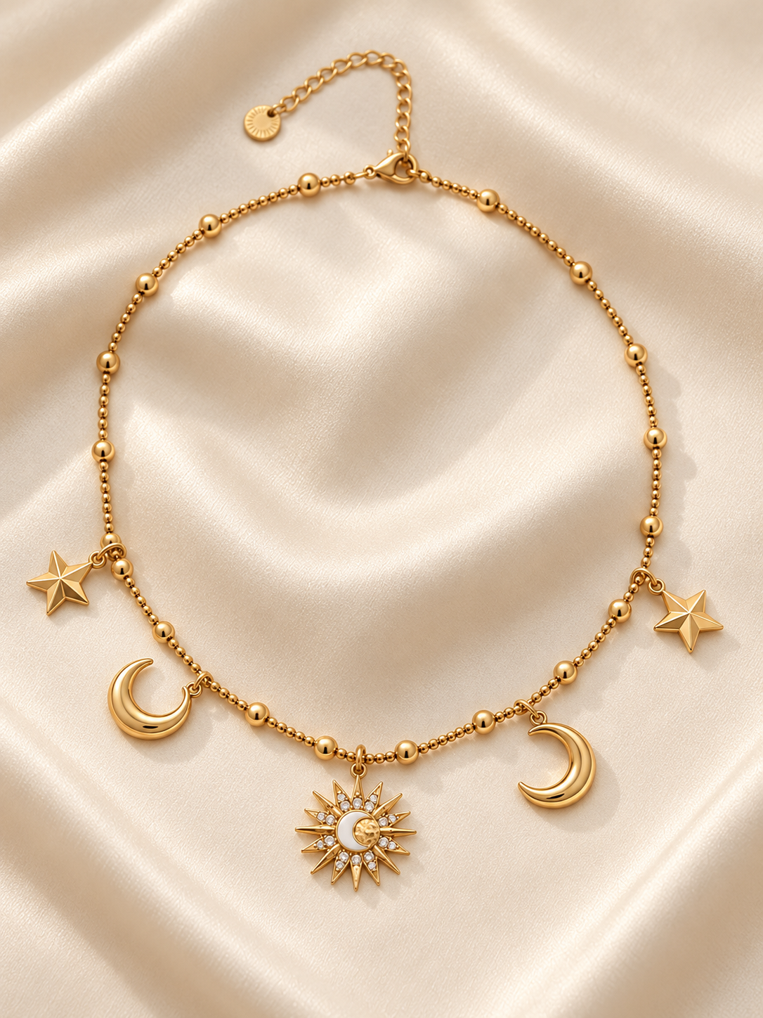 Collier Maëlle posé sur satin beige, étoiles, lunes dorées et soleil