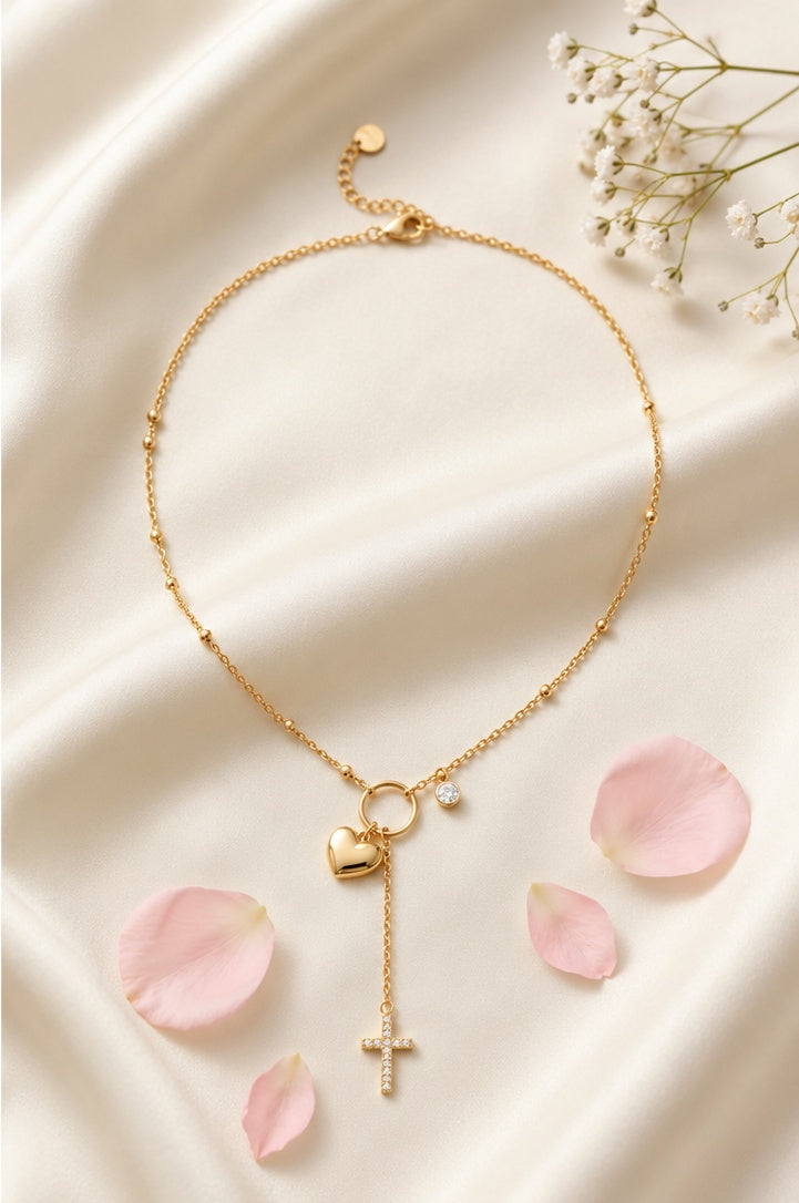 Collier Sofia doré avec cœur et croix scintillante posé sur fond beige